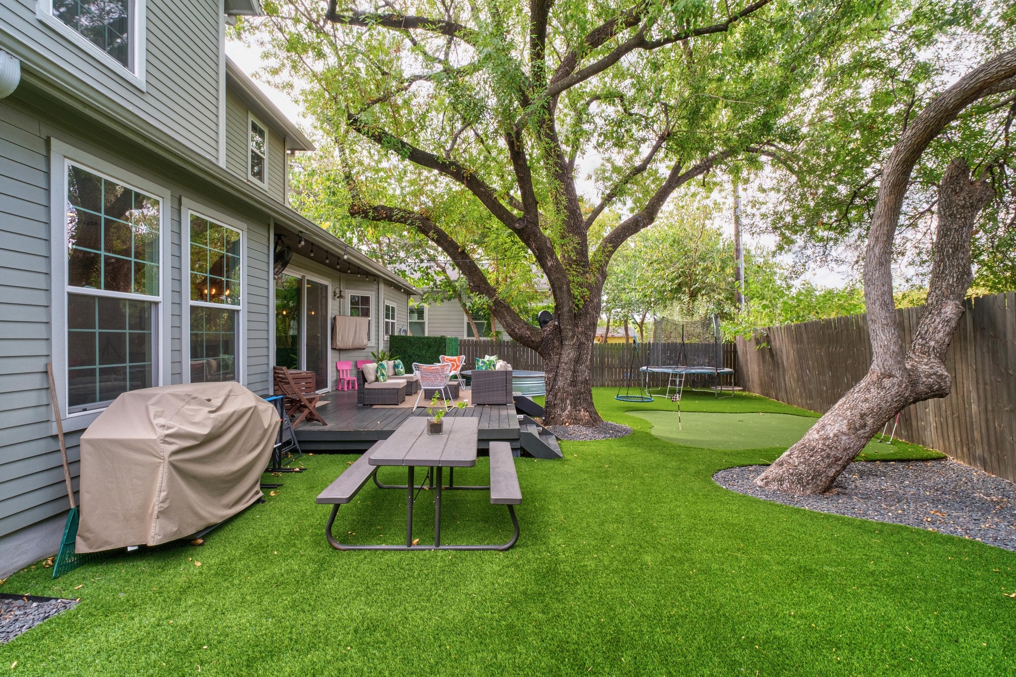 3302 Funston Street Austin, TX 78703 - Photo 27 of 35 Fenced backyard with a trampoline, an outdoor living space, and a wooden deck