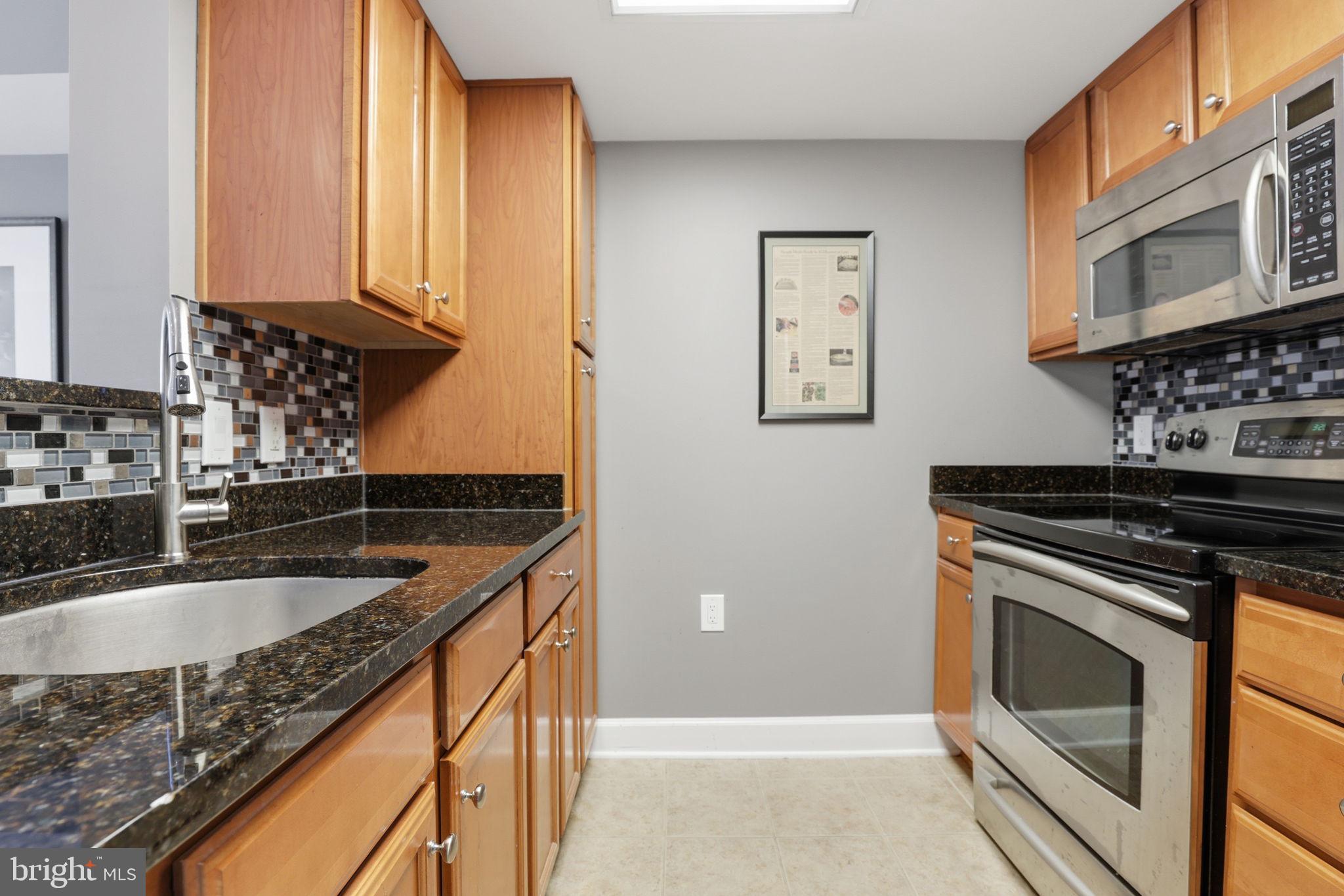 11800 Sunset Hills Road, Unit 218 Reston, VA 20190 - Photo 5 of 38 a kitchen with granite countertop a sink stove and cabinets