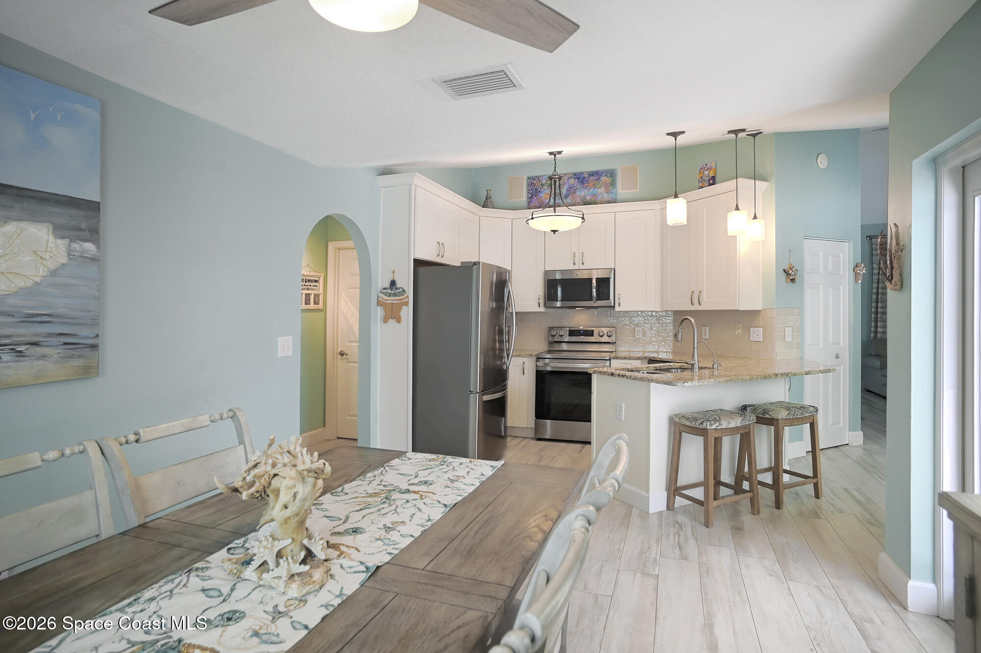 103 Matanzas Road Melbourne Beach, FL 32951 - Photo 14 of 37 a kitchen with stainless steel appliances kitchen island granite countertop a refrigerator stove oven and white cabinets with wooden floor