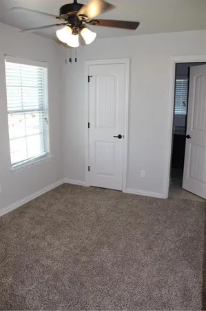 an empty room with a chandelier fan and windows