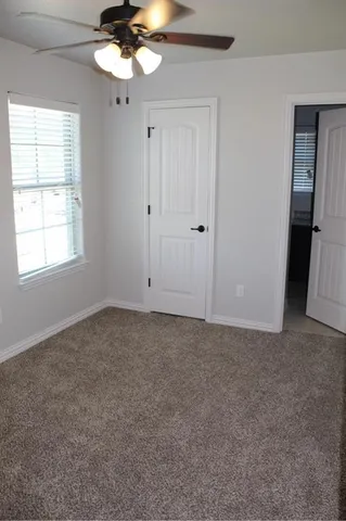 an empty room with a chandelier fan and windows