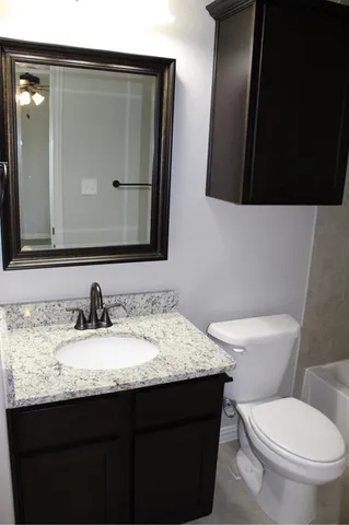 a bathroom with a granite countertop sink a mirror and a toilet