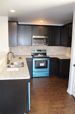 a kitchen with kitchen island granite countertop a sink stove and refrigerator