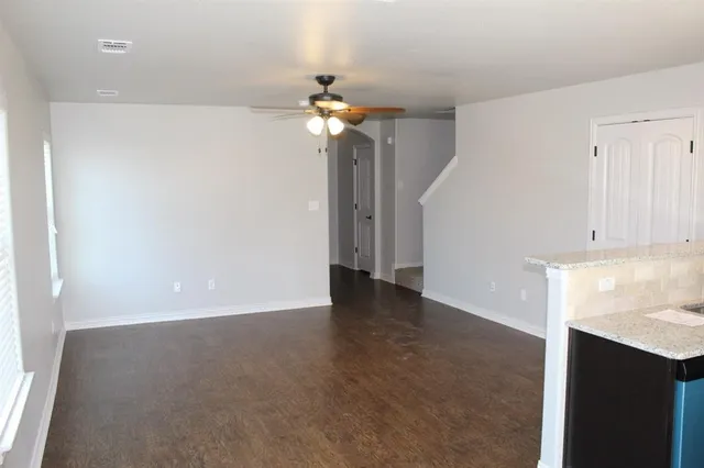 a view of an empty room with window and chandelier fan