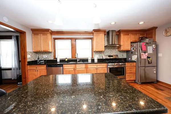 a kitchen with stainless steel appliances granite countertop a refrigerator a stove and a sink with wooden floor