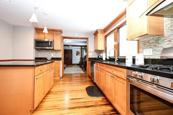 a large kitchen with stainless steel appliances a large counter top a stove a sink and a refrigerator