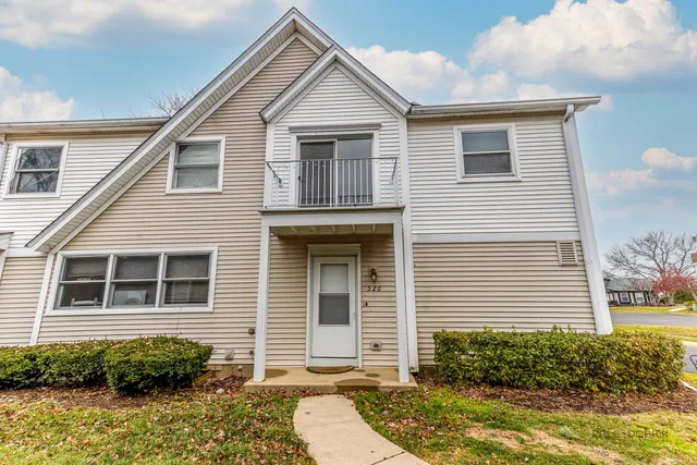 a view of a house with small yard plants and large tree
