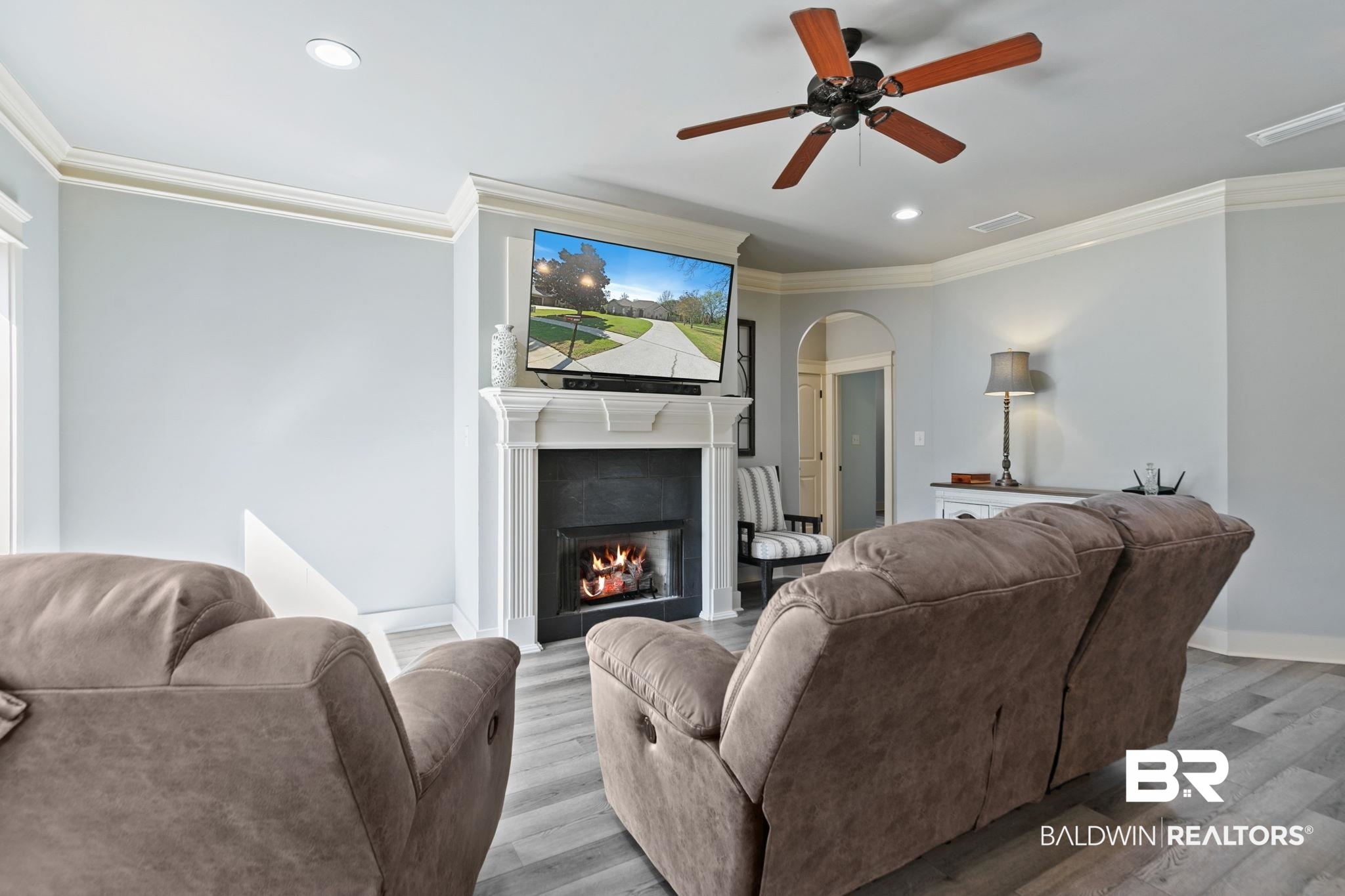 9584 Sanibel Loop Daphne, AL 36526 - Photo 10 of 48 Living room featuring ornamental molding, arched walkways, wood finished floors, a tile fireplace, and a ceiling fan