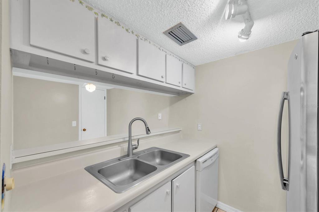 171 Medallion Boulevard, Unit F Madeira Beach, FL 33708 - Photo 11 of 30 a kitchen with stainless steel appliances granite countertop a sink a refrigerator and a counter top