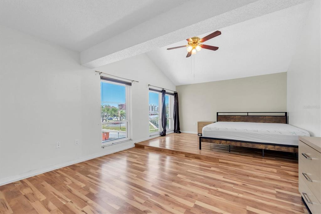 171 Medallion Boulevard, Unit F Madeira Beach, FL 33708 - Photo 13 of 30 a bedroom with a bed and a chandelier