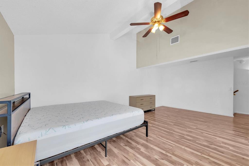 171 Medallion Boulevard, Unit F Madeira Beach, FL 33708 - Photo 14 of 30 a bedroom with a bed and a chandelier fan