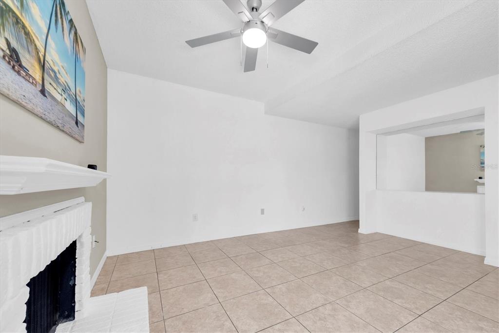 171 Medallion Boulevard, Unit F Madeira Beach, FL 33708 - Photo 7 of 30 a view of an empty room with chandelier fan and fire place