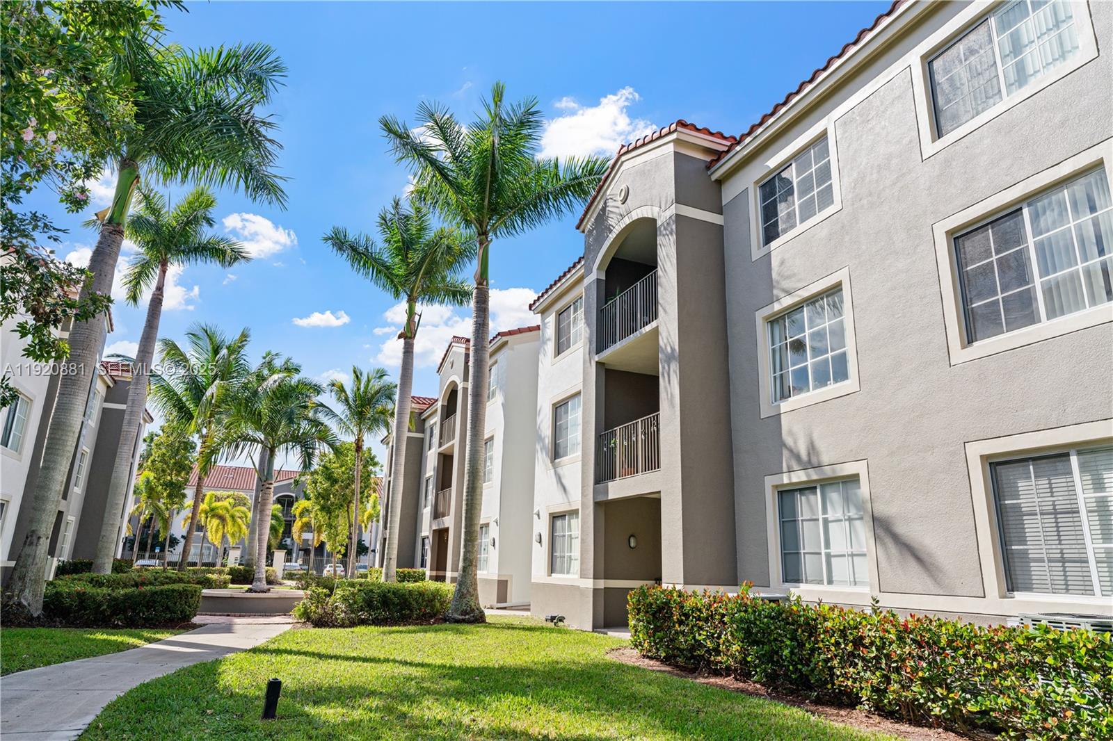 6821 Southwest 44th Street, Unit 203 Miami, FL 33155 - Photo 3 of 28 front view of a building with a yard and palm trees