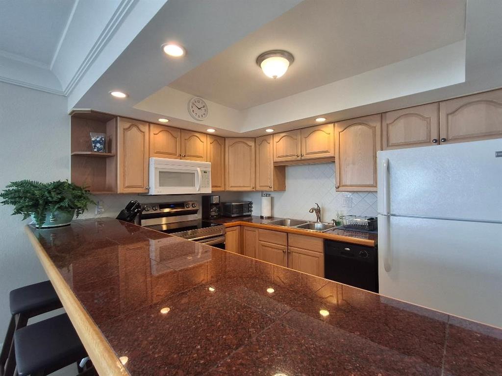 1421 South Ocean Boulevard, Unit 318 Pompano Beach, FL 33062 - Photo 12 of 36 a kitchen with granite countertop a stove a sink a refrigerator a counter space and cabinets