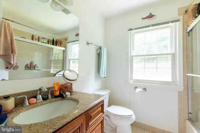 a bathroom with a granite countertop sink mirror vanity and toilet