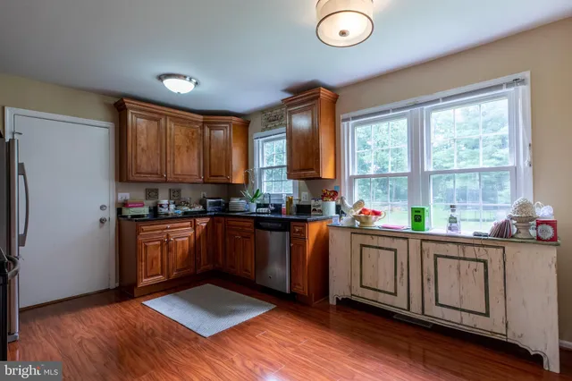 a kitchen with stainless steel appliances granite countertop a stove a sink dishwasher and a microwave with wooden floor