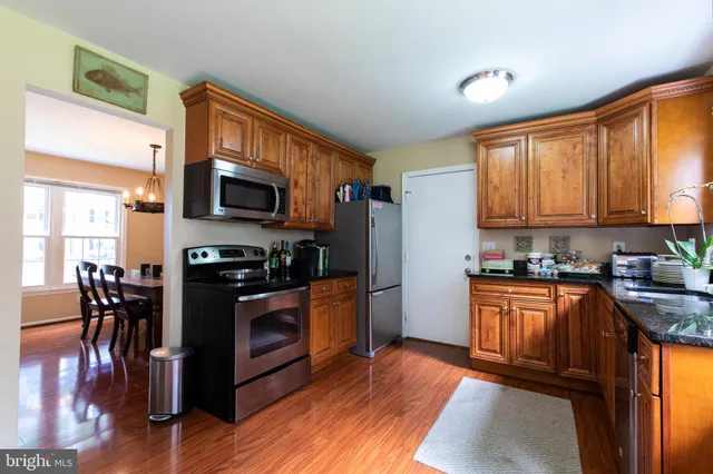 a kitchen with stainless steel appliances granite countertop a stove top oven a sink dishwasher a dining table and chairs with wooden floor