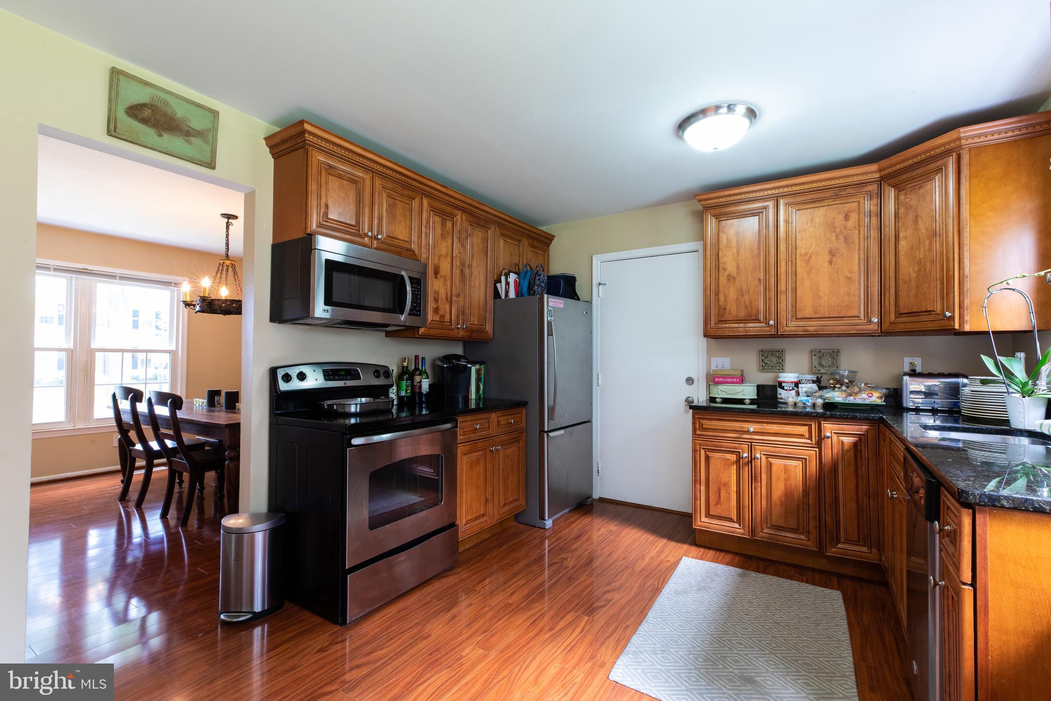 2527 Lindley Terrace Rockville, MD 20850 - Photo 9 of 31 a kitchen with stainless steel appliances granite countertop a stove top oven a sink dishwasher a dining table and chairs with wooden floor