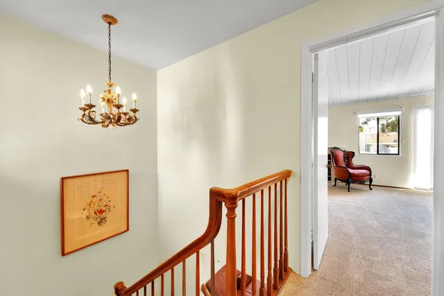 a view of a hallway with furniture and chandelier