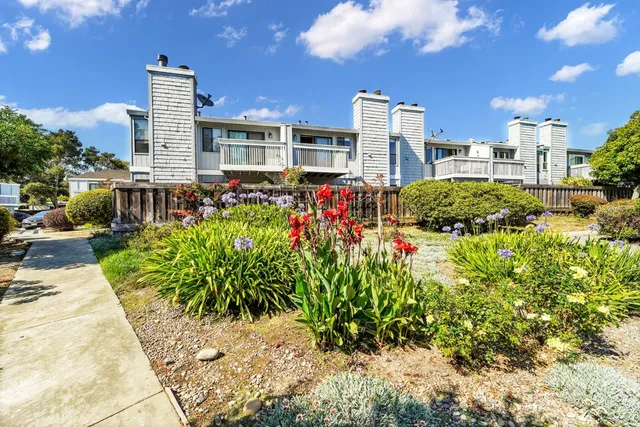 a front view of a multi story residential apartment building with yard and retail shops