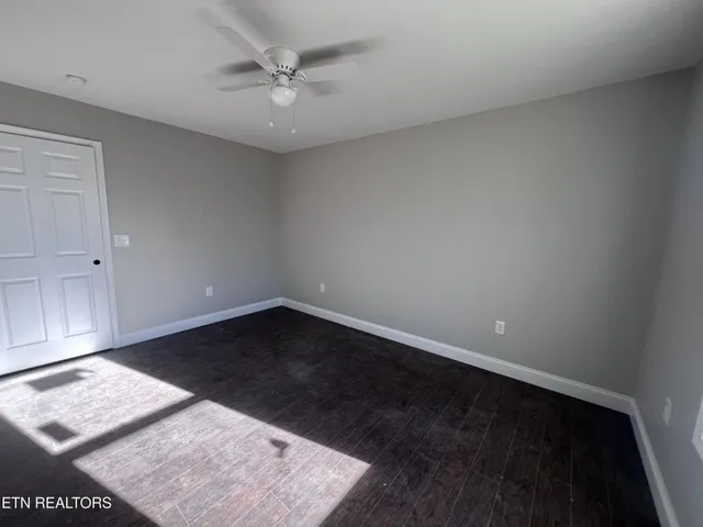 an empty room with a ceiling fan and a window