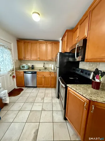 a kitchen with stainless steel appliances granite countertop a stove top oven a sink dishwasher and a refrigerator