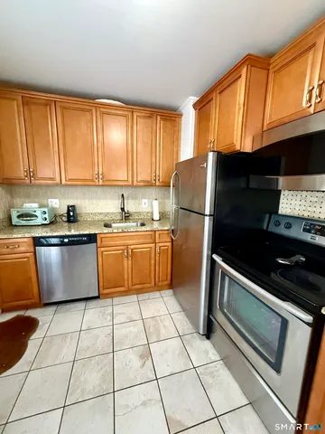 a kitchen with granite countertop a refrigerator stove top oven and sink