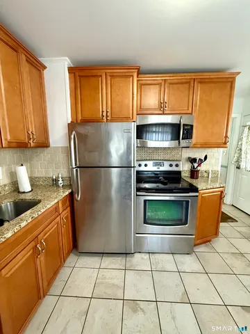 a kitchen with stainless steel appliances granite countertop a refrigerator sink and stove