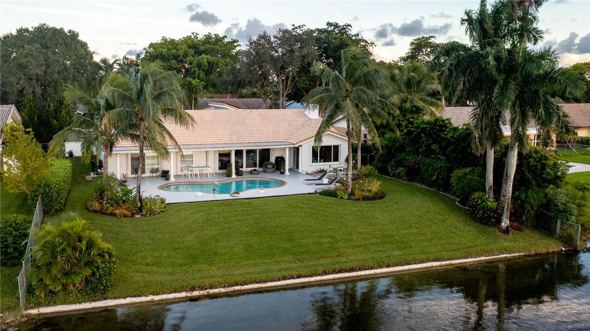 3404 Bridge Road Cooper City, FL 33026 - Photo 76 of 88 a view of a white house with a yard table and chairs