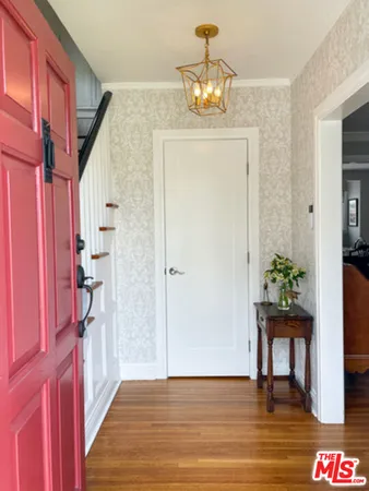 a view of a hallway to a livingroom with furniture wooden floor windows and a chandelier