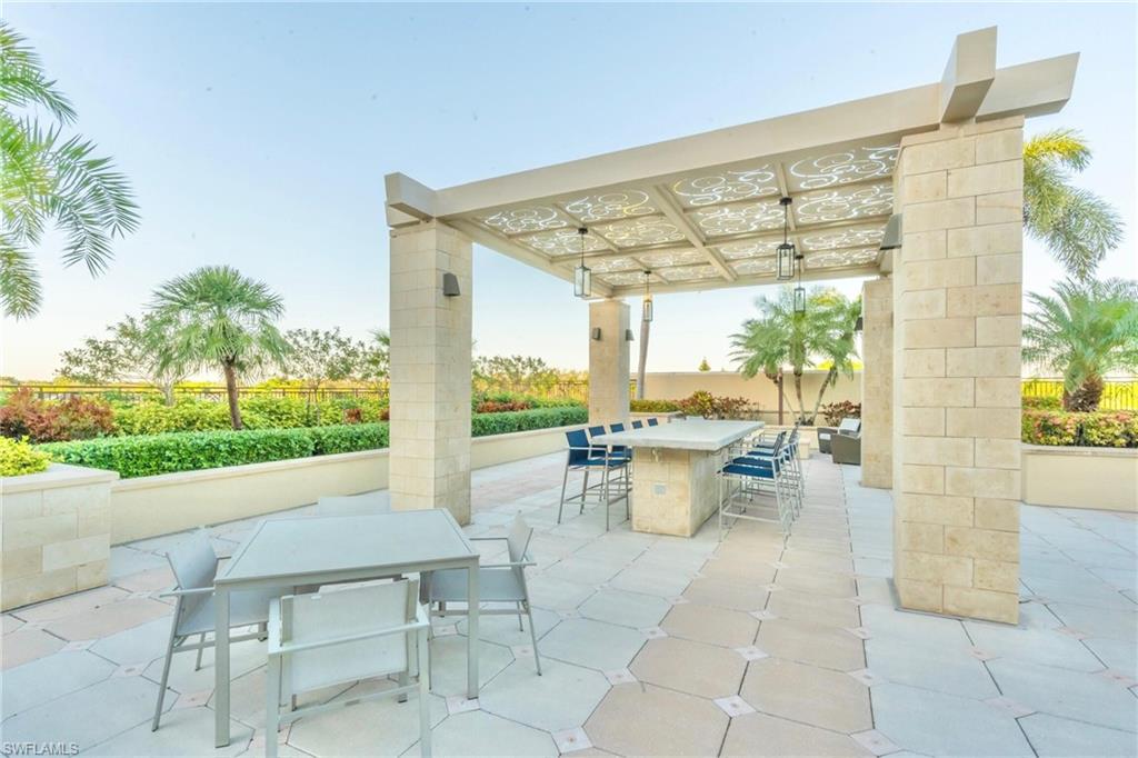9115 Strada Place, Unit 5317 Naples, FL 34108 - Photo 25 of 30 a view of a patio with dining table and chairs with garden view