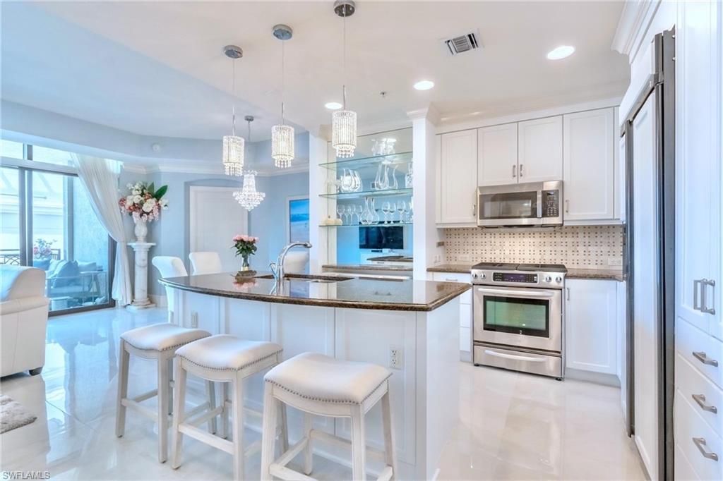 9115 Strada Place, Unit 5317 Naples, FL 34108 - Photo 7 of 30 a kitchen with stainless steel appliances granite countertop a kitchen island hardwood floor sink and stove
