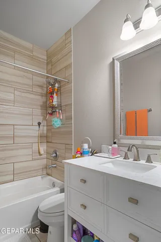 a bathroom with a tub sink vanity mirror and toilet