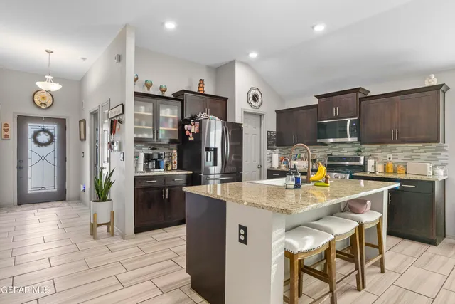 a kitchen with stainless steel appliances granite countertop a refrigerator oven a sink dishwasher and a stove with wooden cabinets