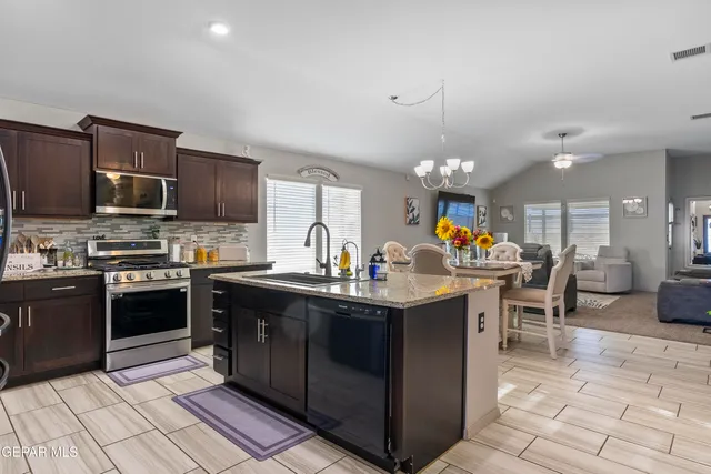 a kitchen with stainless steel appliances granite countertop a sink a stove top oven a counter space and cabinets