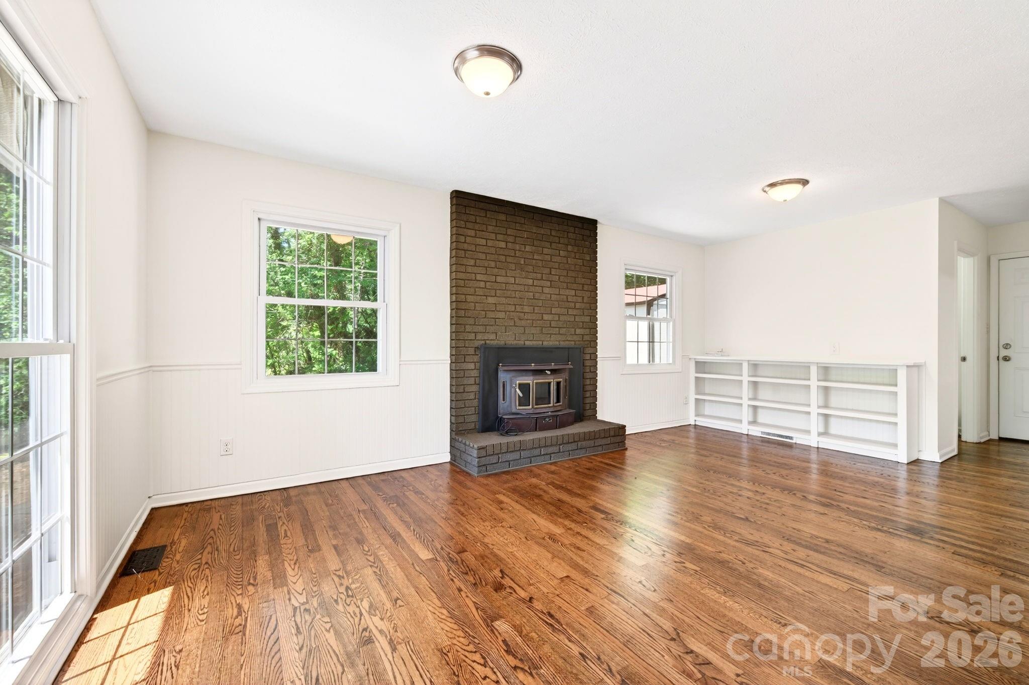 34 Wolfe Cove Road Asheville, NC 28804 - Photo 4 of 42 an empty room with wooden floor fireplace and windows