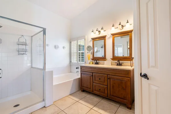 a spacious bathroom with a double vanity sink a mirror and a bathtub
