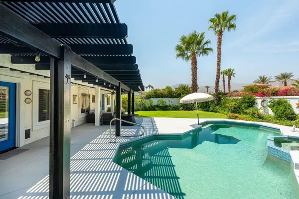 a view of a chairs and table in patio with swimming pool