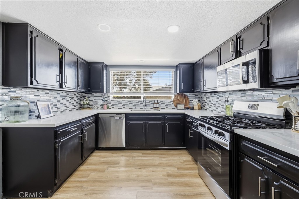 1032 South Farragut Street Ridgecrest, CA 93555 - Photo 11 of 22 a kitchen with stainless steel appliances granite countertop a stove a sink dishwasher and a microwave oven with wooden cabinets