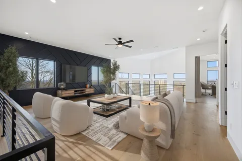 a living room with furniture a ceiling fan and a floor to ceiling window