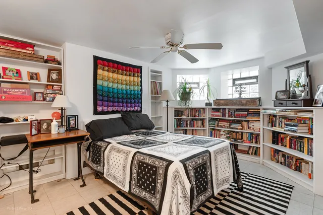 a bedroom with a bed a book shelf and a window