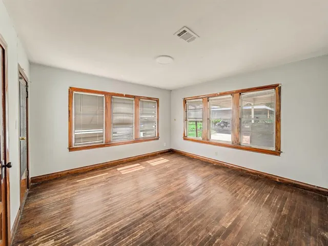 a view of an empty room with a window and wooden floor
