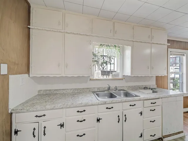 a kitchen with granite countertop white cabinets and window
