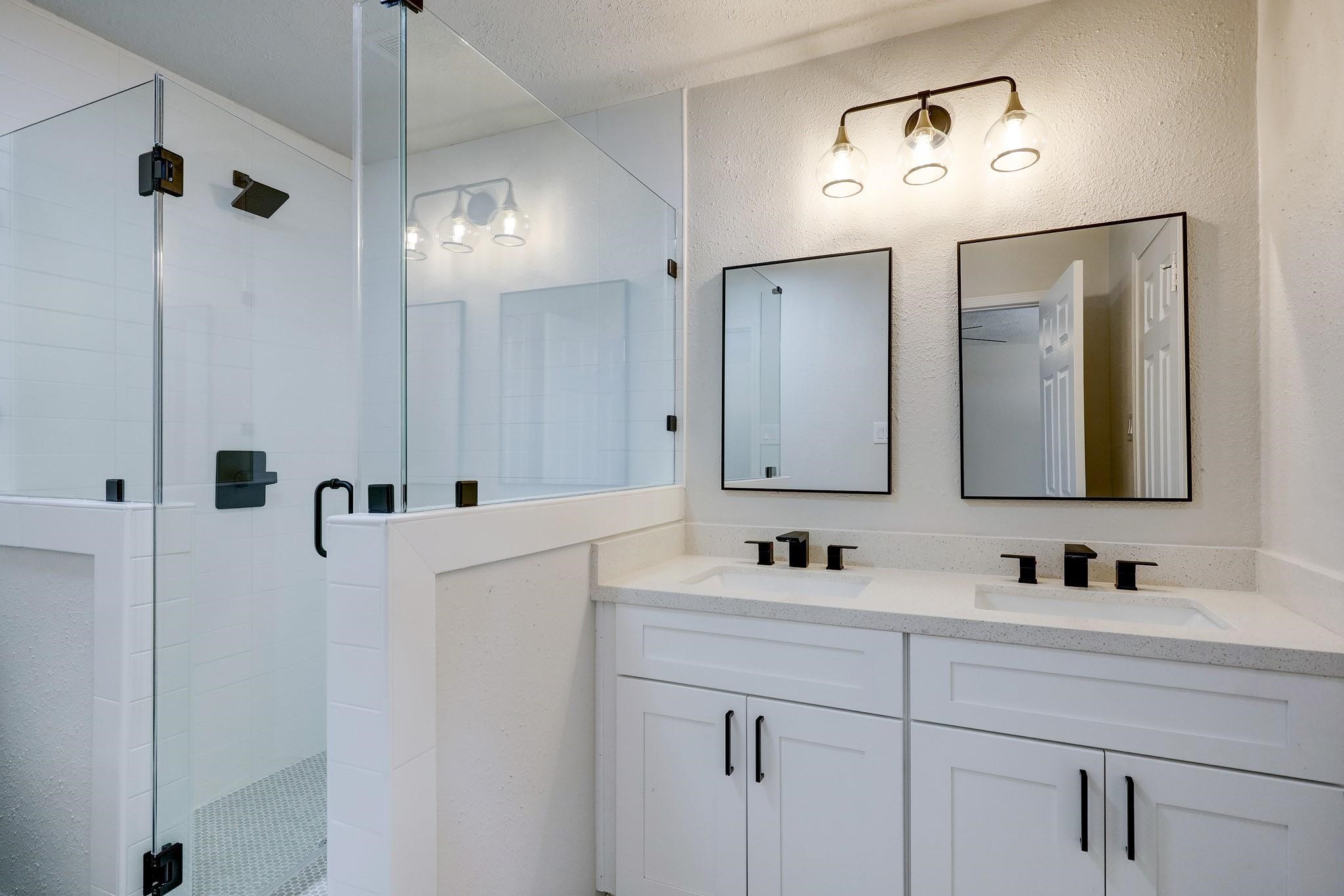 9723 Galston Lane Spring, TX 77379 - Photo 21 of 24 Beautifully updated, the primary bathroom offers dual sinks with black-framed mirrors, coordinating fixtures, and a glass-enclosed shower. A balanced blend of style and functionality.