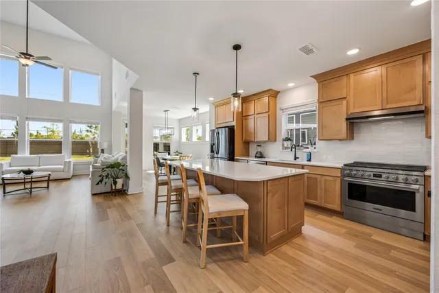 a kitchen with stainless steel appliances granite countertop wooden floors stove and white cabinets