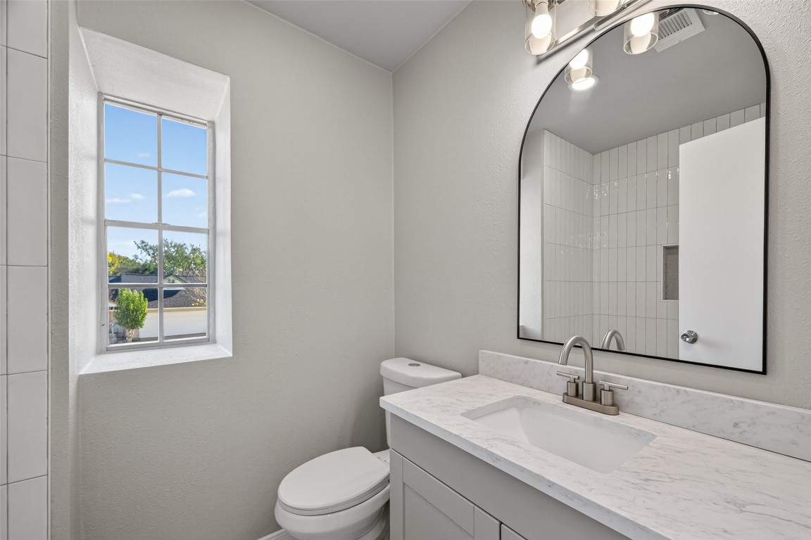 11406 Caesar Drive Houston, TX 77477 - Photo 23 of 32 a bathroom with a granite countertop toilet a sink and mirror
