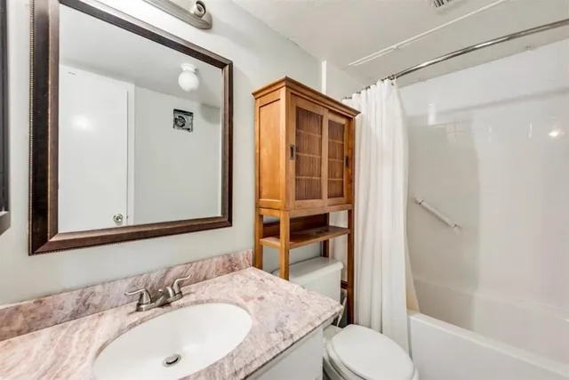 a bathroom with a granite countertop sink toilet and shower