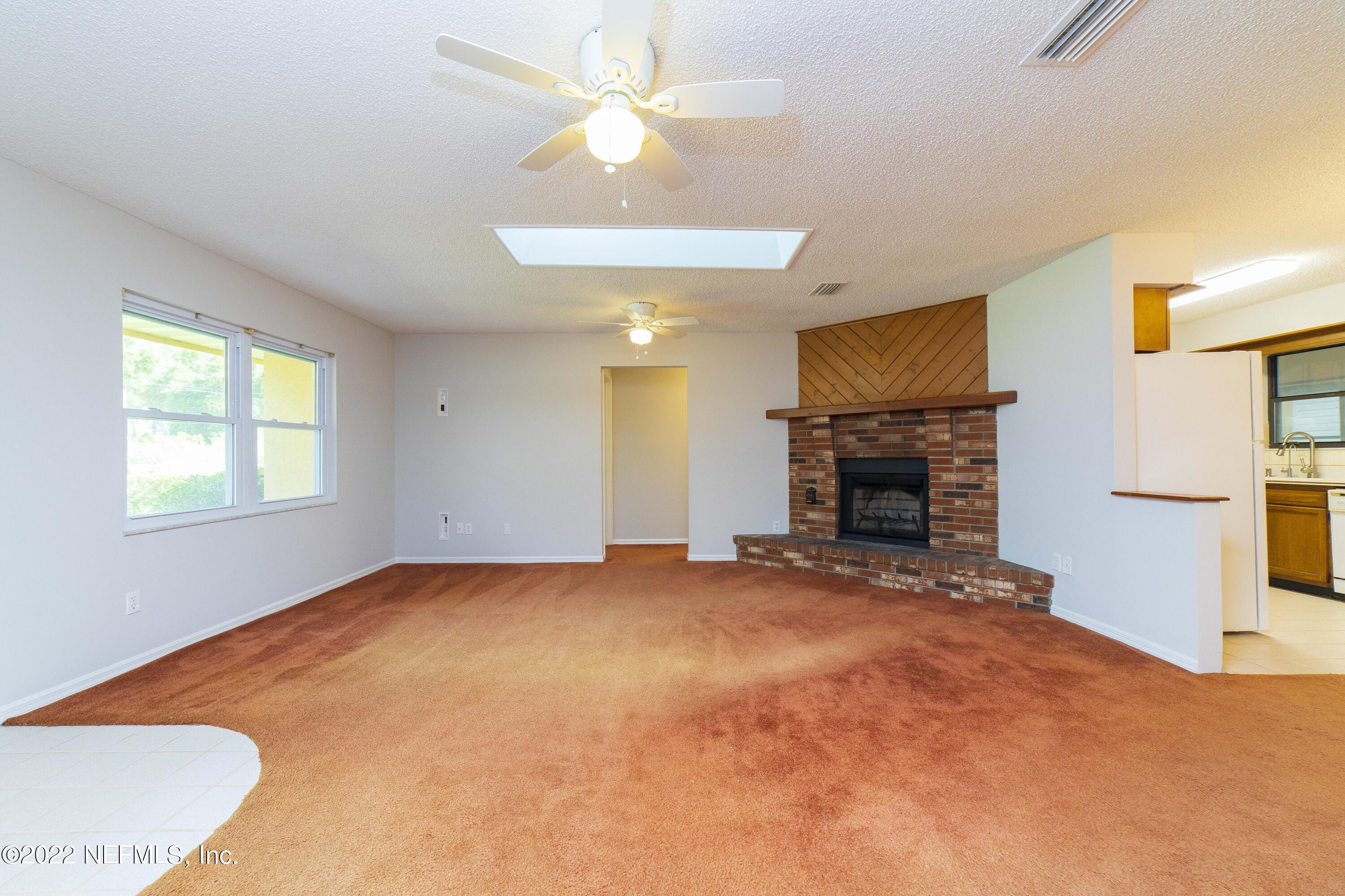 138 Drake Road St. Augustine, FL 32086 - Photo 8 of 46 an empty room with windows fireplace and a ceiling fan