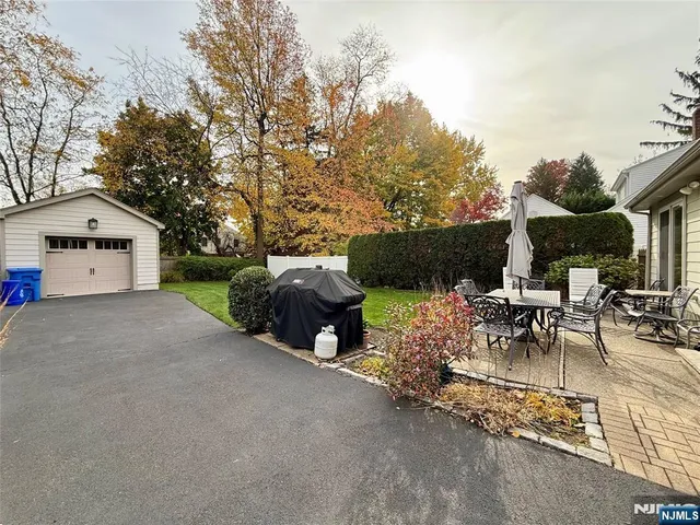 a view of a patio with table and chairs potted plants and a large tree