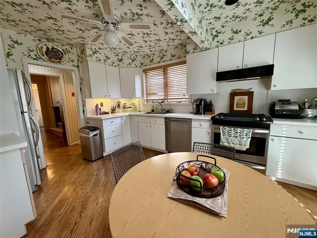 a kitchen with stainless steel appliances a stove a sink dishwasher and a refrigerator with wooden floor